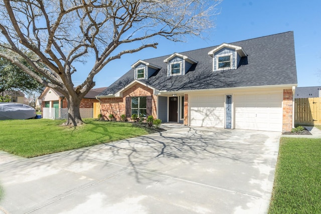 new england style home featuring driveway, fence, a front yard, an attached garage, and brick siding