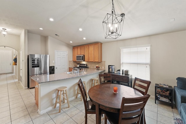 dining space featuring arched walkways, visible vents, light tile patterned flooring, and vaulted ceiling