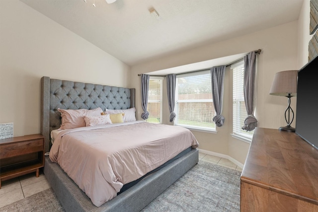 bedroom with vaulted ceiling, light tile patterned floors, and baseboards