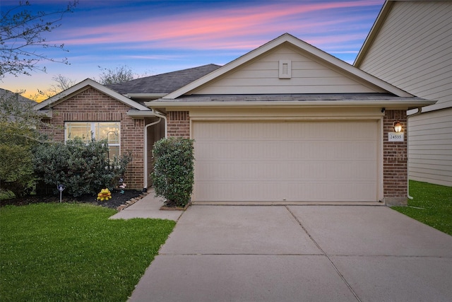 ranch-style home with driveway, roof with shingles, a garage, a lawn, and brick siding