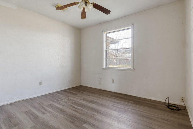 spare room featuring baseboards, wood finished floors, and a ceiling fan