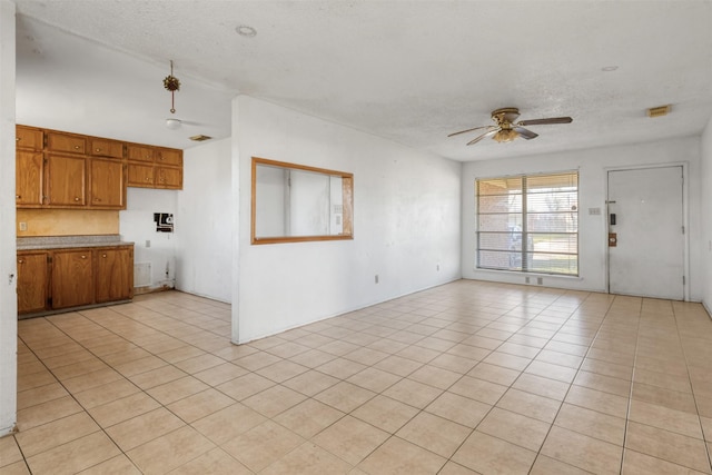 unfurnished living room featuring a textured ceiling, light tile patterned flooring, and a ceiling fan