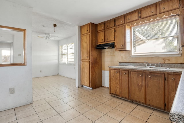 kitchen featuring ceiling fan, under cabinet range hood, light countertops, brown cabinets, and a sink