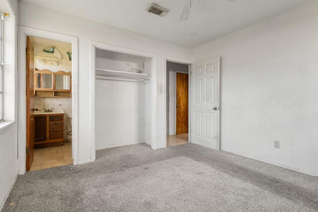 unfurnished bedroom with visible vents, ceiling fan, a closet, ensuite bathroom, and carpet flooring