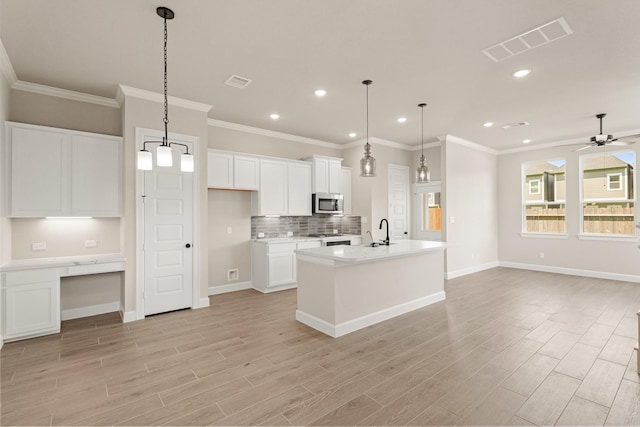5617 Iris Harvest Dr, Houston, TX 77091 - kitchen featuring stainless steel microwave, recessed lighting, open floor plan, light wood-type flooring, and white cabinets