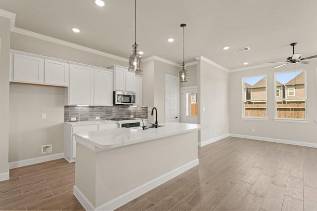 5617 Iris Harvest Dr, Houston, TX 77091 - kitchen featuring stainless steel microwave, light wood finished floors, white cabinets, ornamental molding, and backsplash