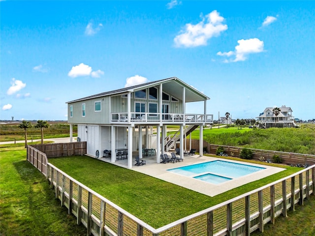 rear view of property with an in ground hot tub, a fenced backyard, stairs, a patio area, and a lawn