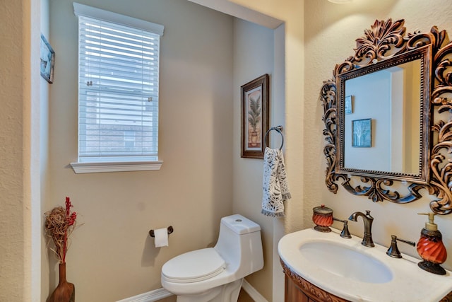 half bathroom with toilet, baseboards, and a sink