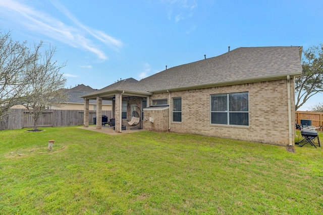 rear view of property featuring a lawn, a fenced backyard, brick siding, and a patio area