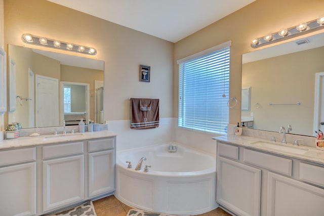 bathroom with a bath, visible vents, two vanities, and a sink