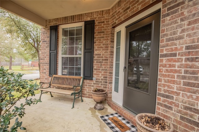 property entrance with brick siding and a porch