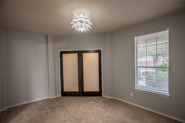 empty room featuring carpet flooring, french doors, and baseboards