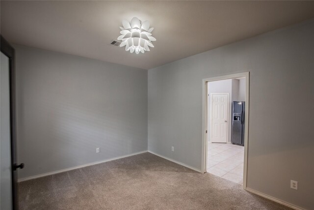 unfurnished room with visible vents, light colored carpet, and baseboards