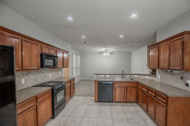 kitchen with a peninsula, light tile patterned flooring, a sink, black appliances, and brown cabinets