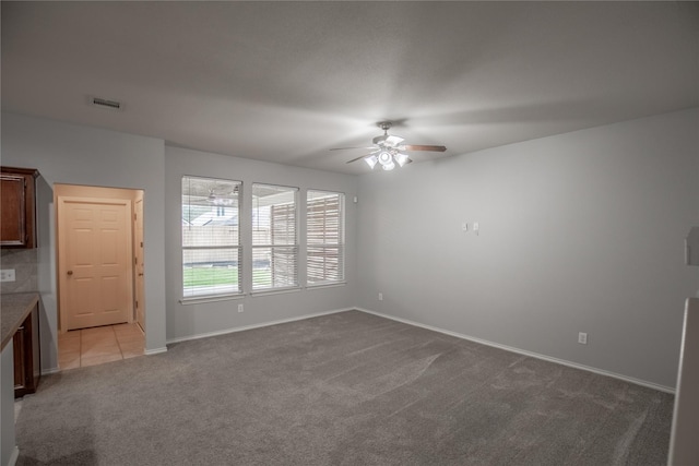 interior space with visible vents, baseboards, carpet, tile patterned floors, and a ceiling fan