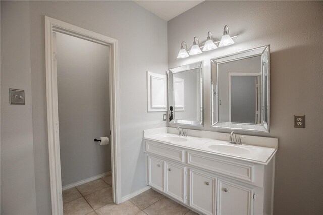 full bathroom with tile patterned floors, double vanity, baseboards, and a sink