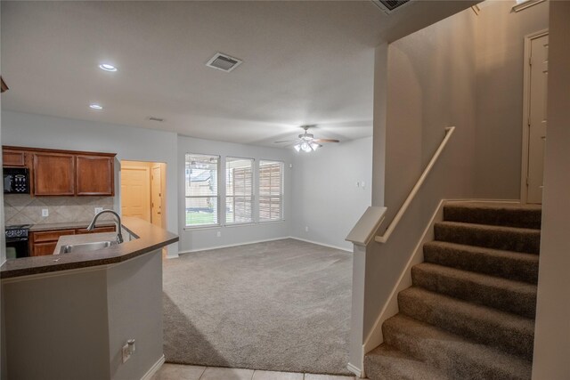 kitchen featuring visible vents, a sink, black appliances, light carpet, and backsplash