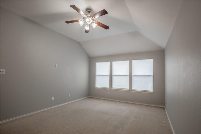 spare room with light carpet, a ceiling fan, baseboards, and vaulted ceiling