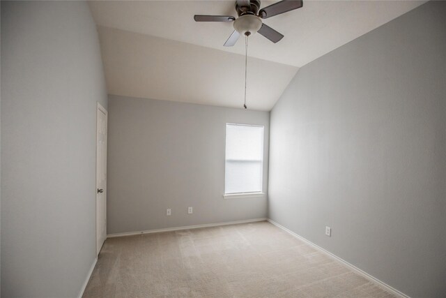 empty room featuring baseboards, lofted ceiling, light carpet, and a ceiling fan