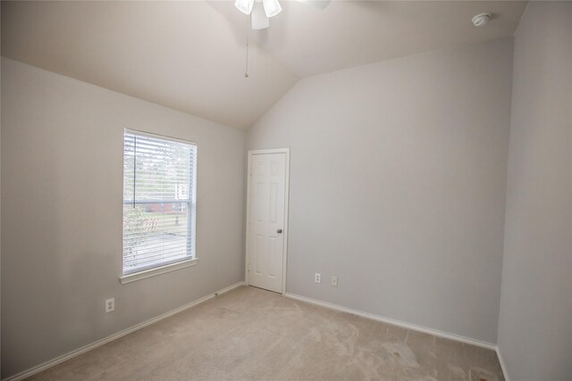 empty room with light colored carpet, baseboards, lofted ceiling, and a ceiling fan