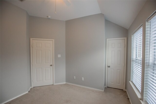 unfurnished bedroom featuring baseboards, lofted ceiling, and light colored carpet