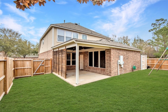 rear view of property with brick siding, ceiling fan, a lawn, a fenced backyard, and a patio area