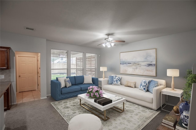 living area with baseboards, ceiling fan, light colored carpet, and visible vents