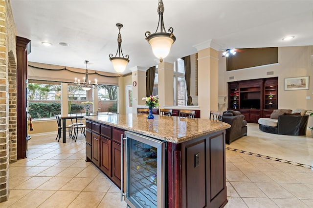 kitchen featuring light tile patterned floors, beverage cooler, light stone countertops, a kitchen island, and pendant lighting