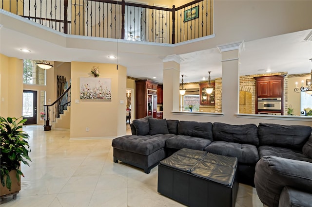 living area featuring decorative columns, baseboards, a towering ceiling, and stairway