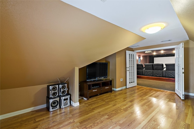 unfurnished living room featuring light wood-type flooring, baseboards, lofted ceiling, and visible vents