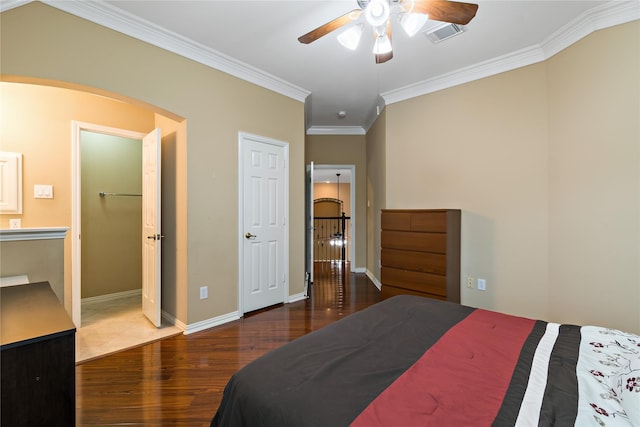 bedroom featuring visible vents, crown molding, baseboards, wood finished floors, and arched walkways