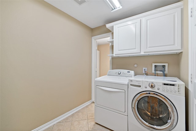 clothes washing area with visible vents, independent washer and dryer, cabinet space, light tile patterned floors, and baseboards