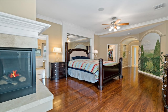 bedroom with crown molding, wood finished floors, visible vents, and a tile fireplace