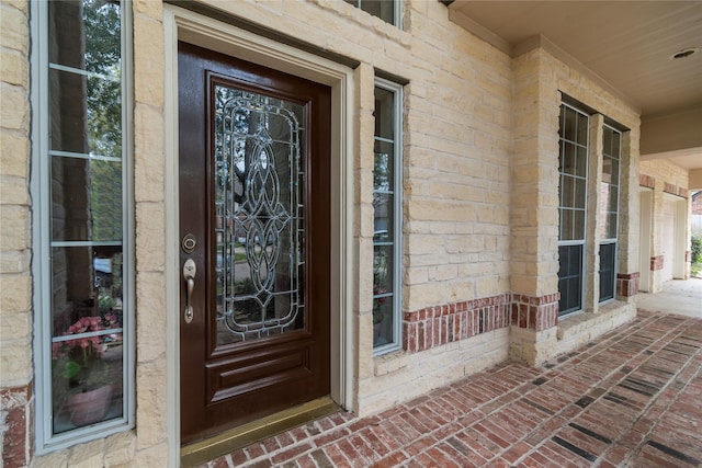 doorway to property featuring a porch and brick siding