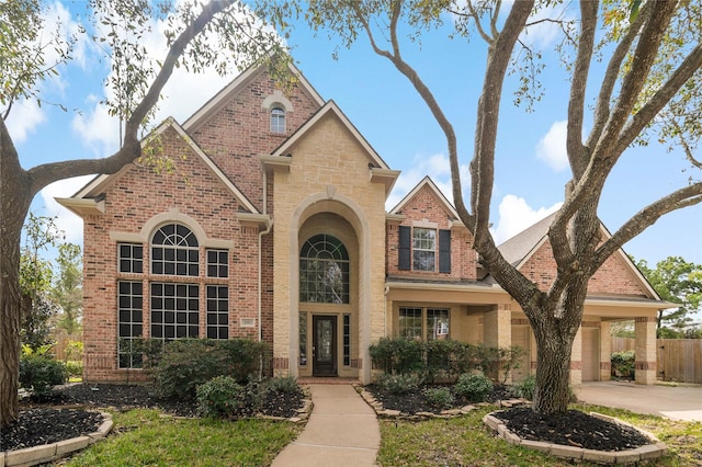 traditional home with fence, an attached garage, concrete driveway, stone siding, and brick siding