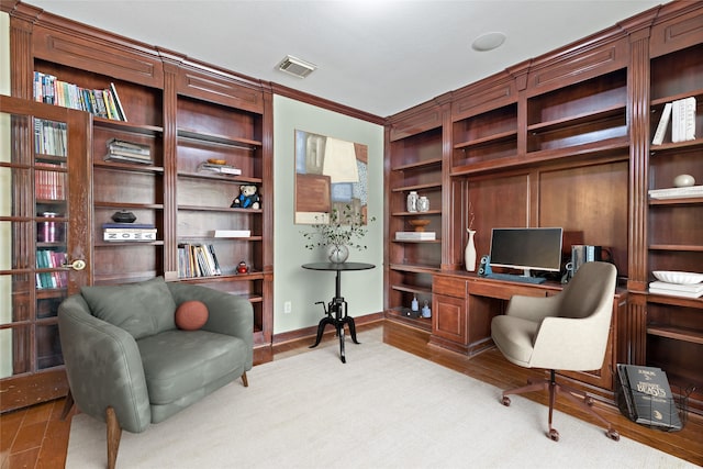 office area featuring visible vents, built in shelves, wood finished floors, crown molding, and baseboards