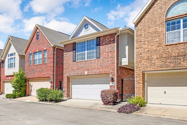 multi unit property featuring a garage, brick siding, and driveway