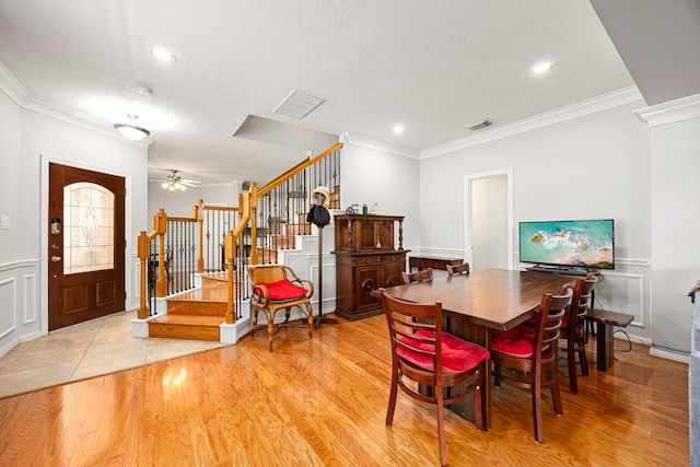 dining space featuring light wood-style flooring, stairs, and crown molding