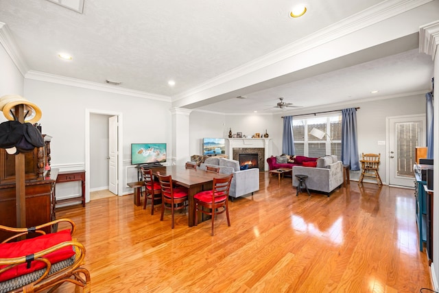 dining room with visible vents, ornate columns, a glass covered fireplace, crown molding, and light wood-type flooring