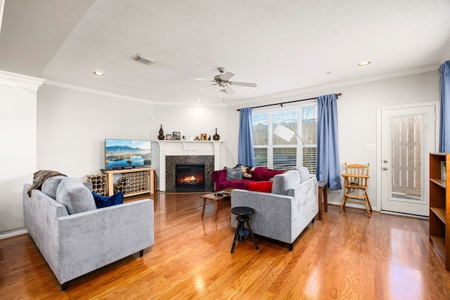 living room featuring visible vents, a fireplace with flush hearth, light wood-style floors, and ornamental molding