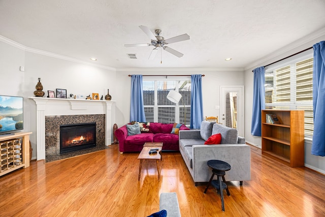 living room with light wood-type flooring, visible vents, ornamental molding, and a fireplace