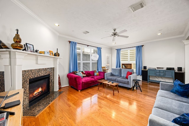 living area with visible vents, light wood-style flooring, and a premium fireplace