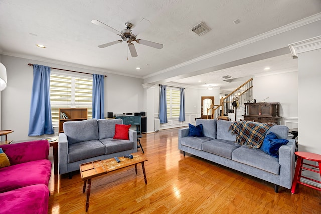 living area with crown molding, stairway, wood finished floors, and visible vents