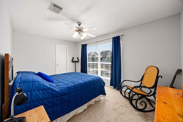 carpeted bedroom with visible vents, a textured ceiling, and ceiling fan