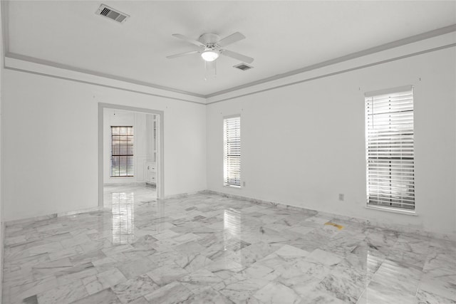 empty room with visible vents, marble finish floor, ornamental molding, and a healthy amount of sunlight