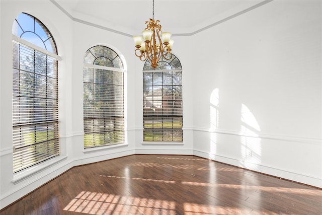 unfurnished dining area featuring ornamental molding, baseboards, an inviting chandelier, and wood-type flooring