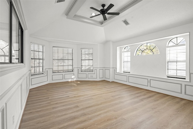 unfurnished room featuring visible vents, light wood-style floors, a healthy amount of sunlight, and a decorative wall