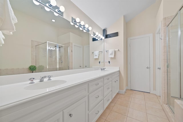 full bath with tile patterned flooring, lofted ceiling, double vanity, a stall shower, and a sink