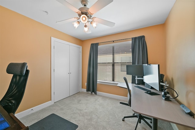 home office with a ceiling fan, baseboards, and light carpet