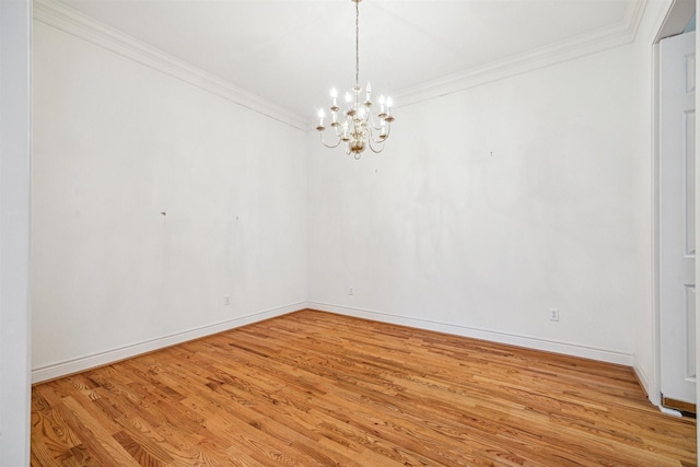 unfurnished room with an inviting chandelier, crown molding, wood finished floors, and baseboards